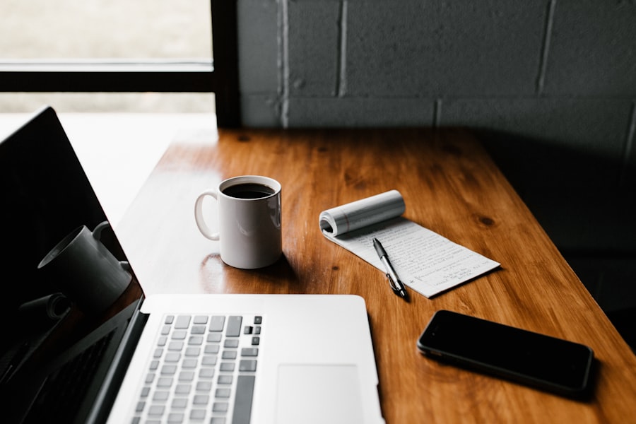 A laptop and notebook on a wooden desk.